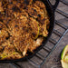 Apple crumble in black cast iron skillet on cooling rack.