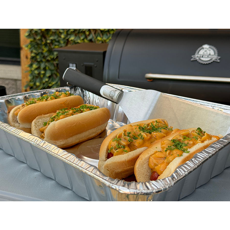 Silver aluminum tray with hot dogs topped with macaroni and cheese and parsley.