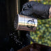 Silver shaker with "Pit Boss" logo, held by gloved hand, dispensing seasoning.
