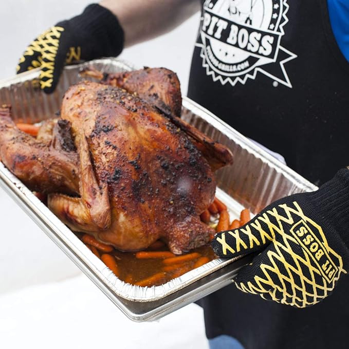Gloves holding pan liners with grilled chicken on it.