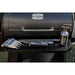 Black Pit Boss grill with accessories: fork, knife, and spray bottle.