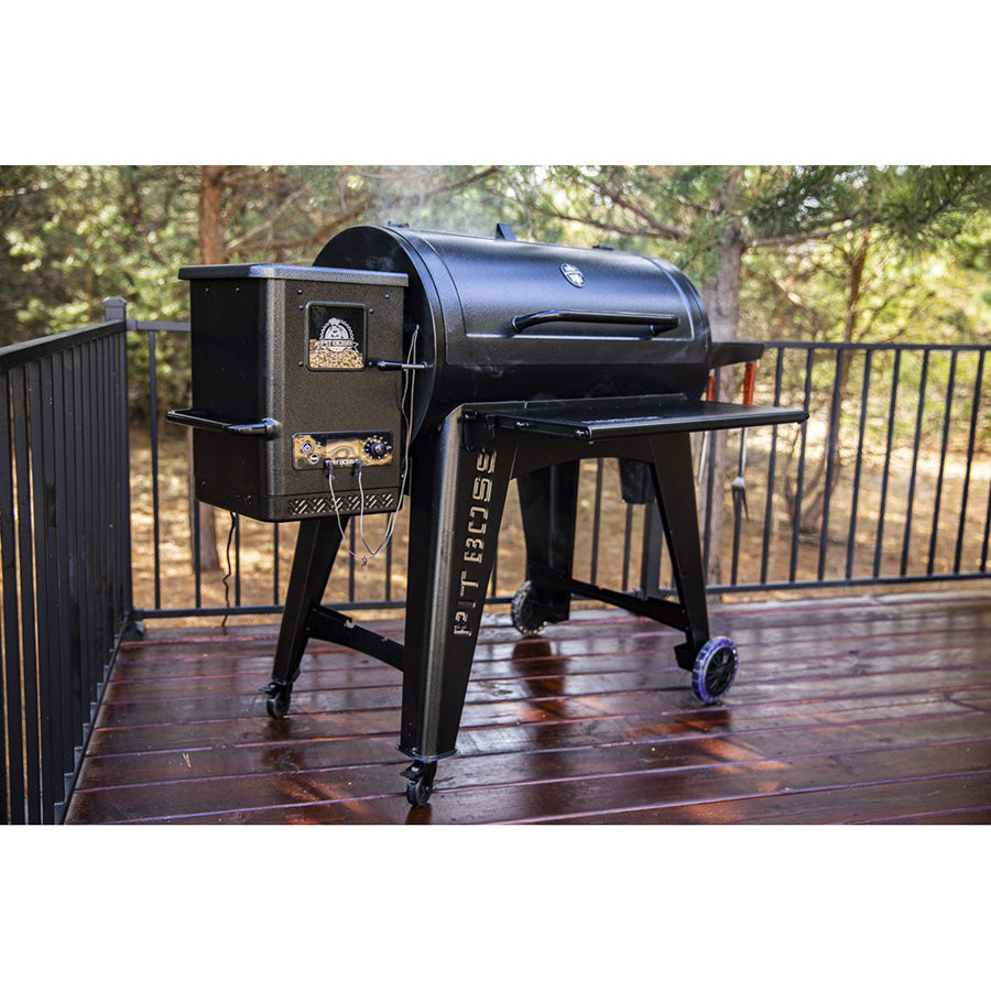 Black Traeger pellet grill on wheels, outdoor deck setting.