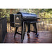 Black Traeger pellet grill on wheels, outdoor deck setting.