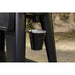 Black bucket hanging from a black stand with outdoor background.