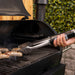 Black grill with tongs flipping sausages outdoors.