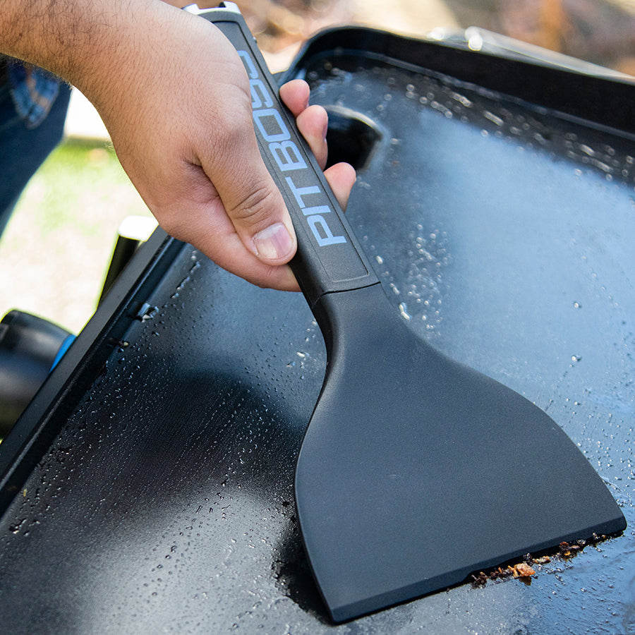 Black PIT8050 scraper cleaning grill surface.