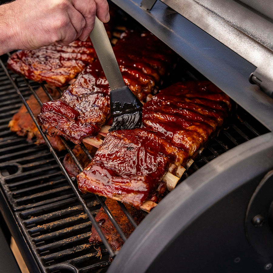 Grilled ribs with barbecue sauce on a black grill.