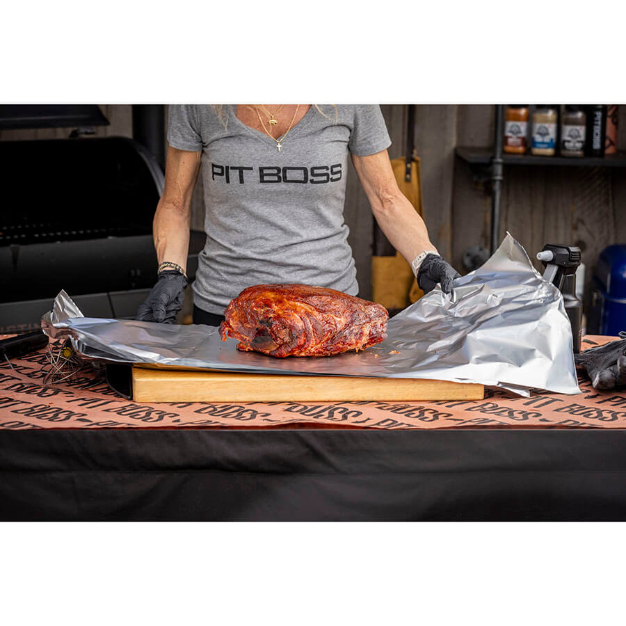 "Person wearing 'PIT BOSS' shirt prepares smoked meat on aluminum foil."