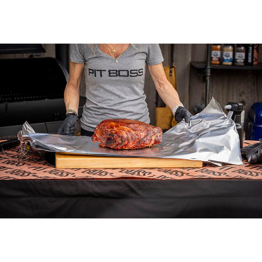 "Person wearing 'PIT BOSS' shirt prepares smoked meat on aluminum foil."