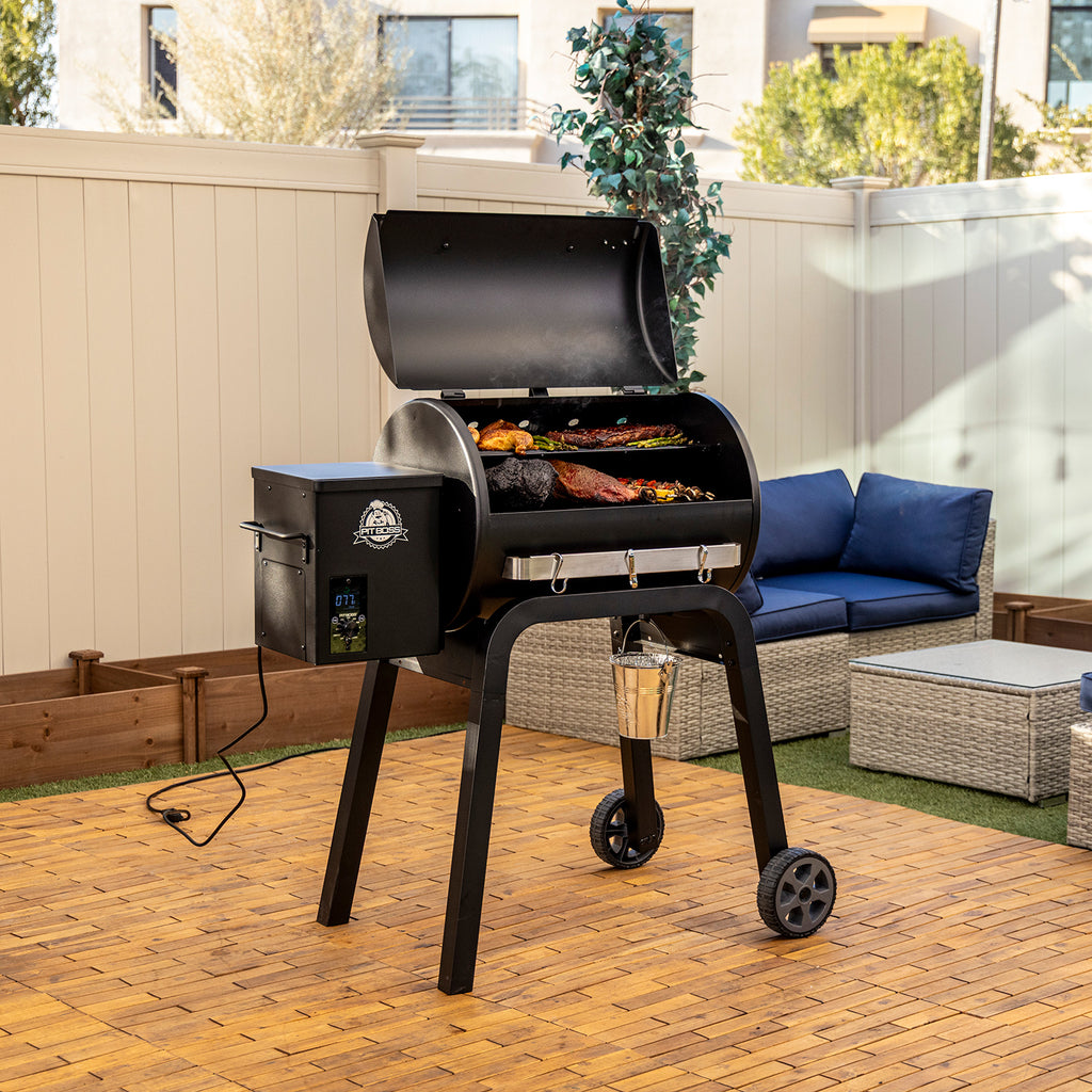 Pit Boss Carbon Series 700 wood pellet grill, side angle with lid open showing food cooking on the grates