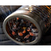 Stainless steel smoker tube filled with burning wood chips, emitting smoke for grilling or BBQ flavor enhancement.