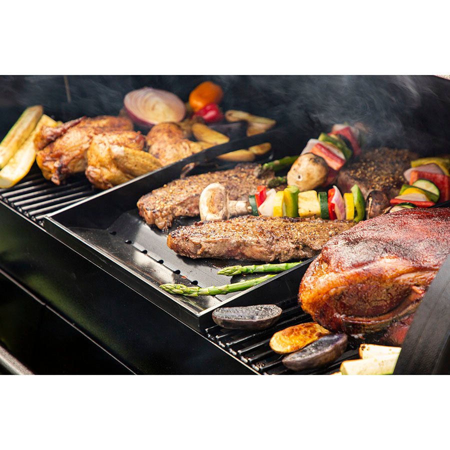 Black grill with steaks, vegetables, and skewers cooking.