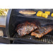 Black grill with smoking meats, corn, and pie.