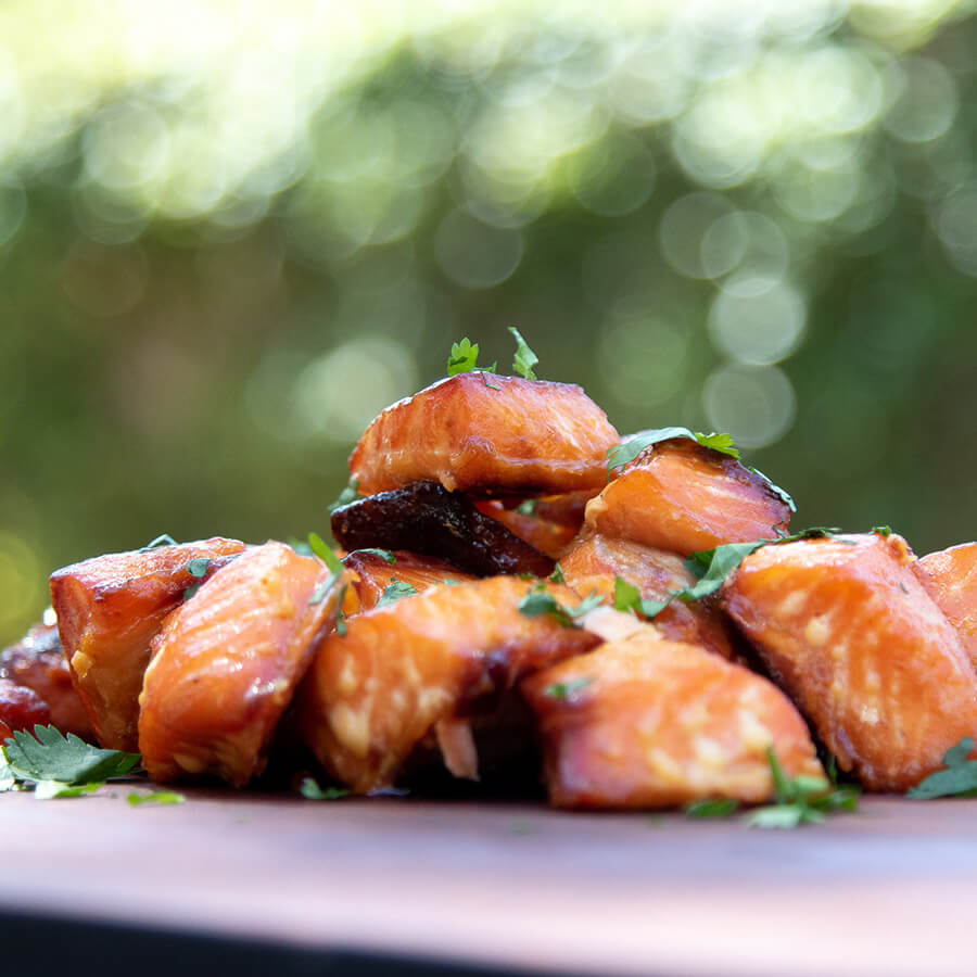 Grilled salmon pieces with parsley garnish on a plate.
