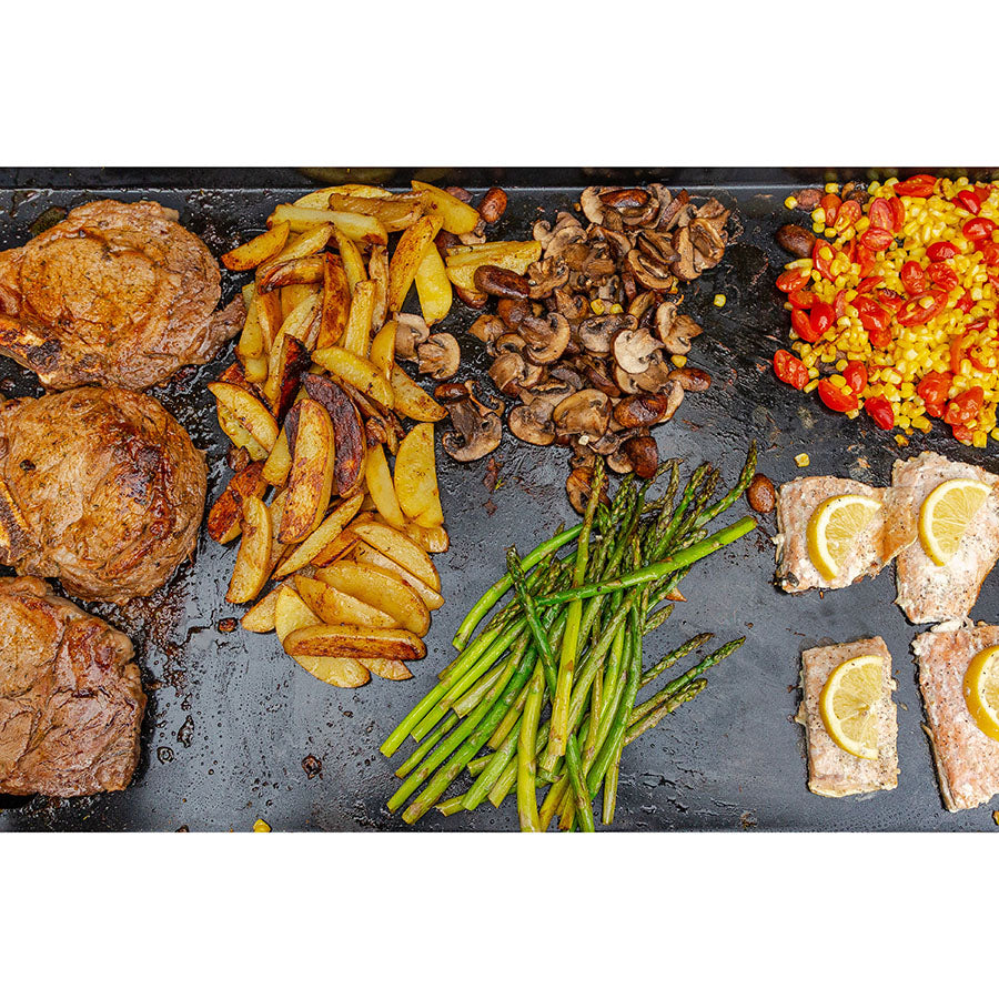 Ceramic griddle top on Pit Boss Grills 4-burner upgrade, showcasing cooked meats, vegetables, and sides.