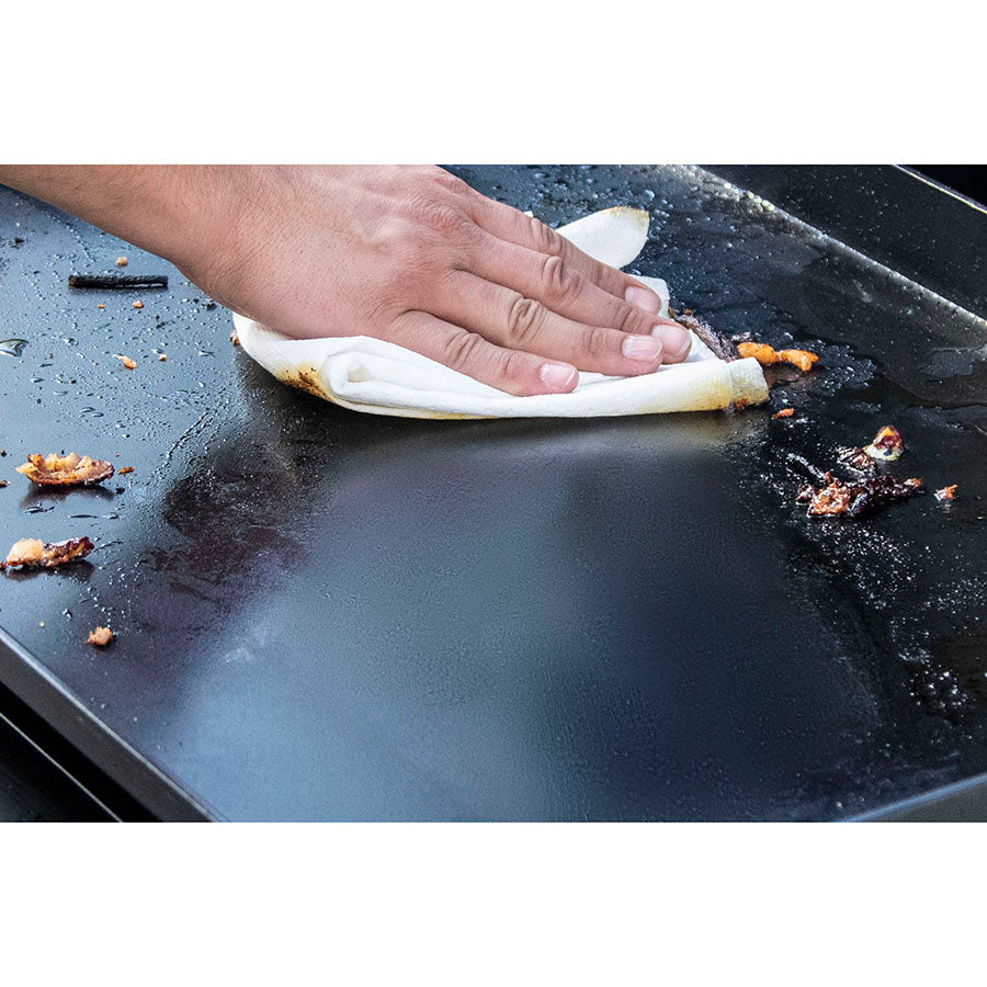 Pit Boss Grills Ceramic Griddle Top - 4 Burner being cleaned with a cloth.